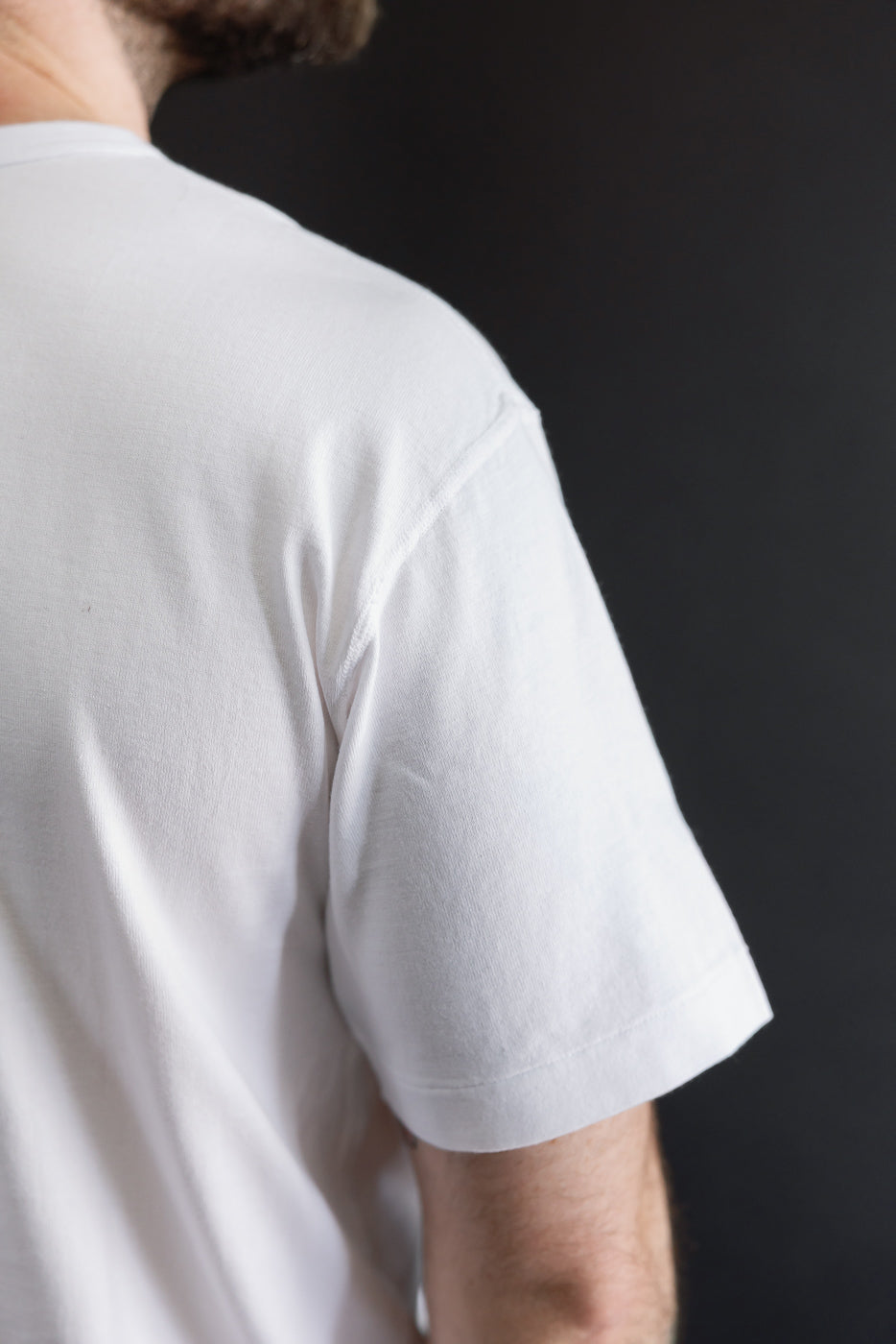 Close-up back view of a white t-shirt sleeve on a male model (5'9