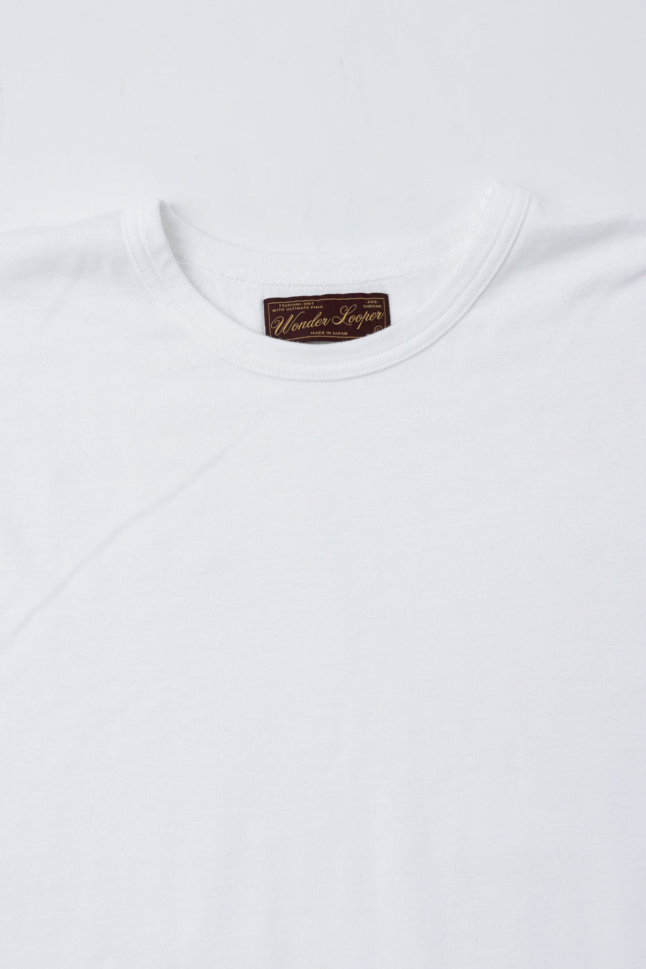 Close-up of the front neckline and interior brand tag of a white t-shirt.