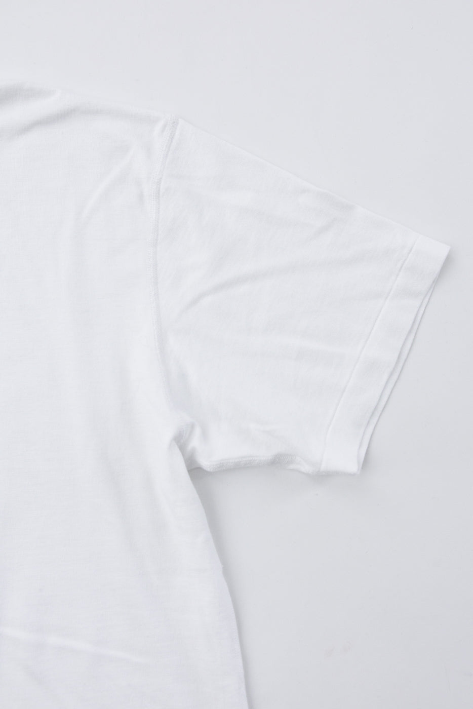 Close-up of the right sleeve and side of a white short-sleeve cotton t-shirt.