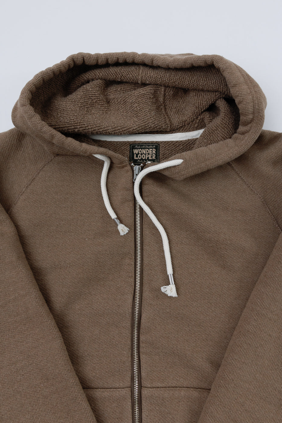 Close-up front view of a brown zip-up hoodie showing the hood, drawstring, and zipper detail.