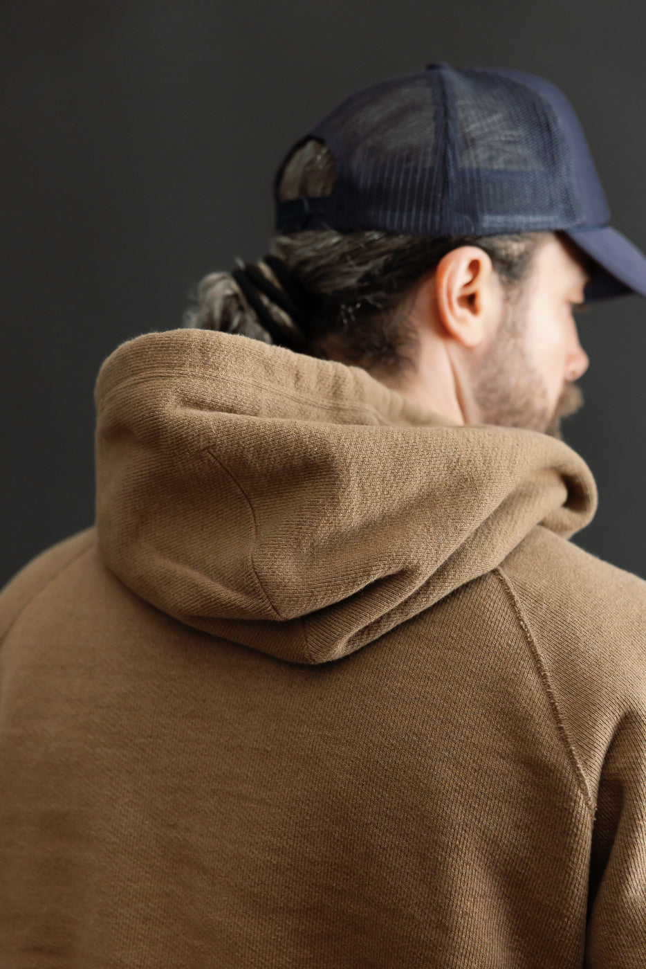 Close-up back view of a tan waffle-knit hoodie on a male model, 5'9