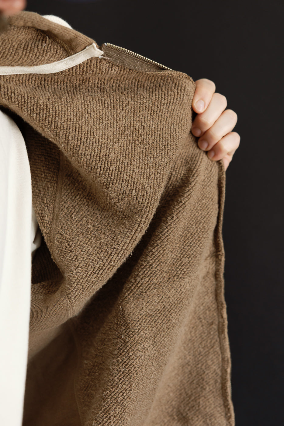 Close-up of the back texture and zipper of a brown textured hoodie worn by a male model.