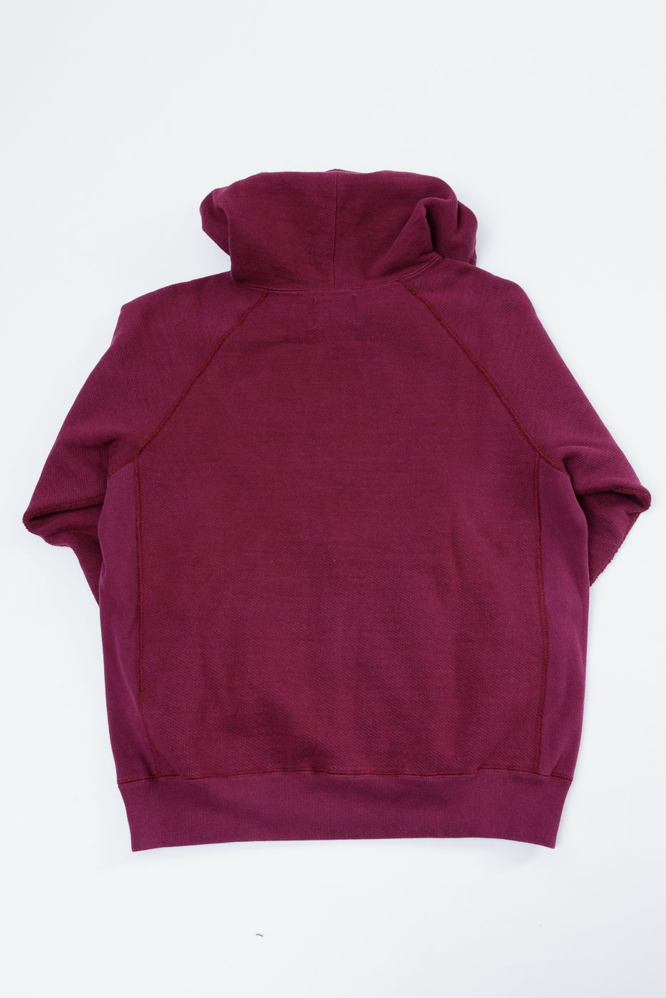 Back view flat lay of a maroon hooded sweatshirt showing raglan sleeves and ribbed hem.