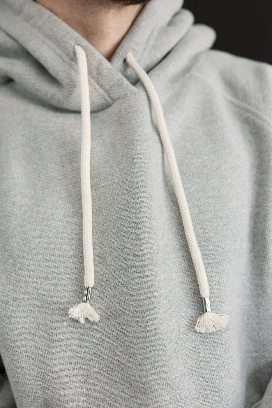 Close-up front view of a grey hoodie on a male model, 5'9