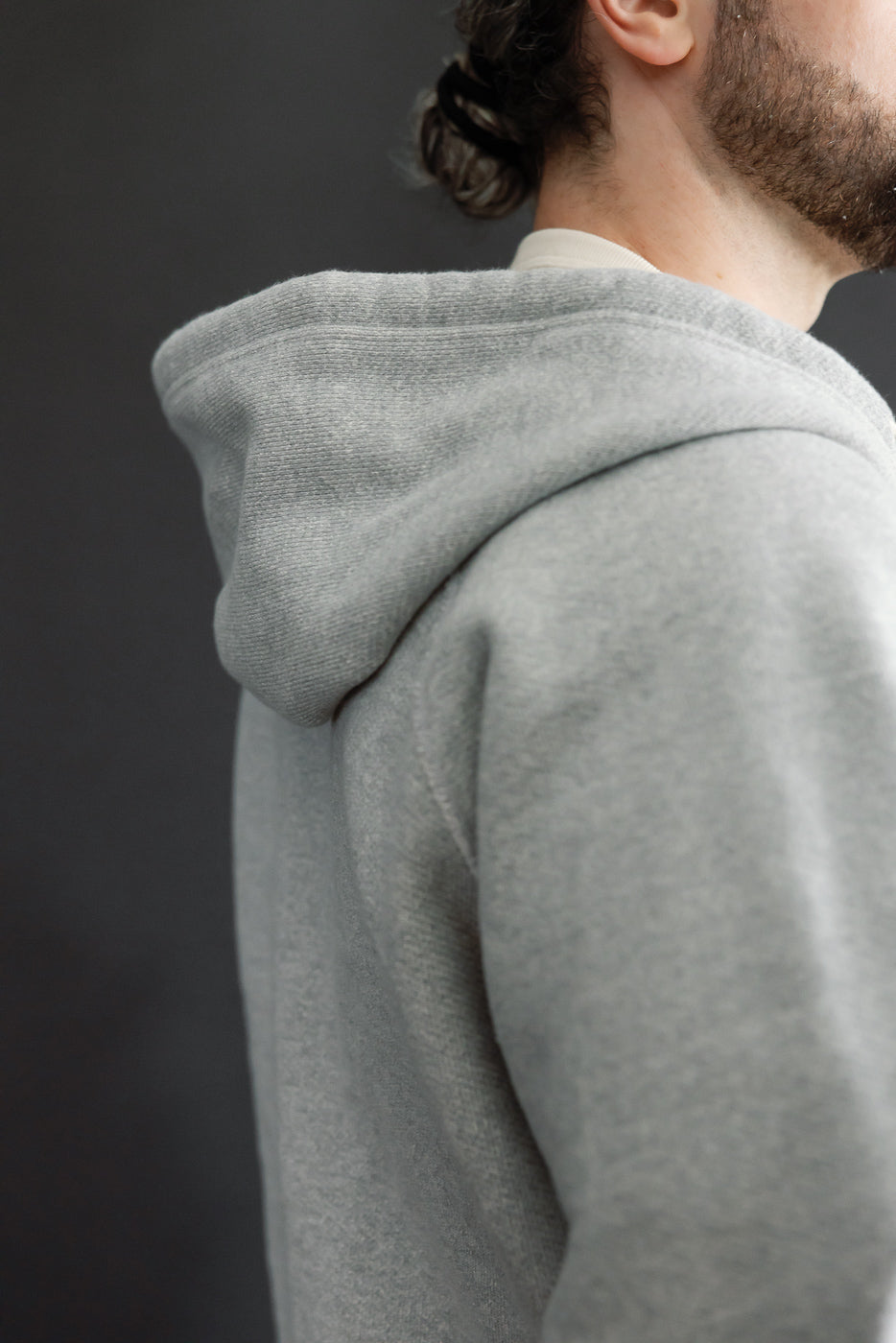 Close-up side view of a grey hoodie hood and shoulder on a male model, 5'9