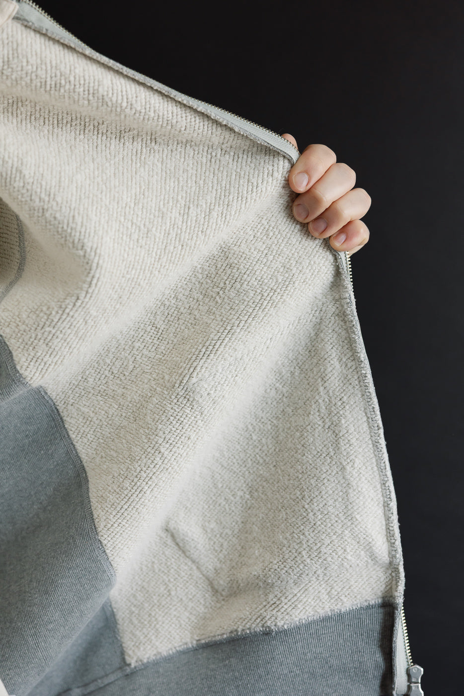 Close-up of the interior terry cloth fabric texture and silver zipper detail on a grey garment.