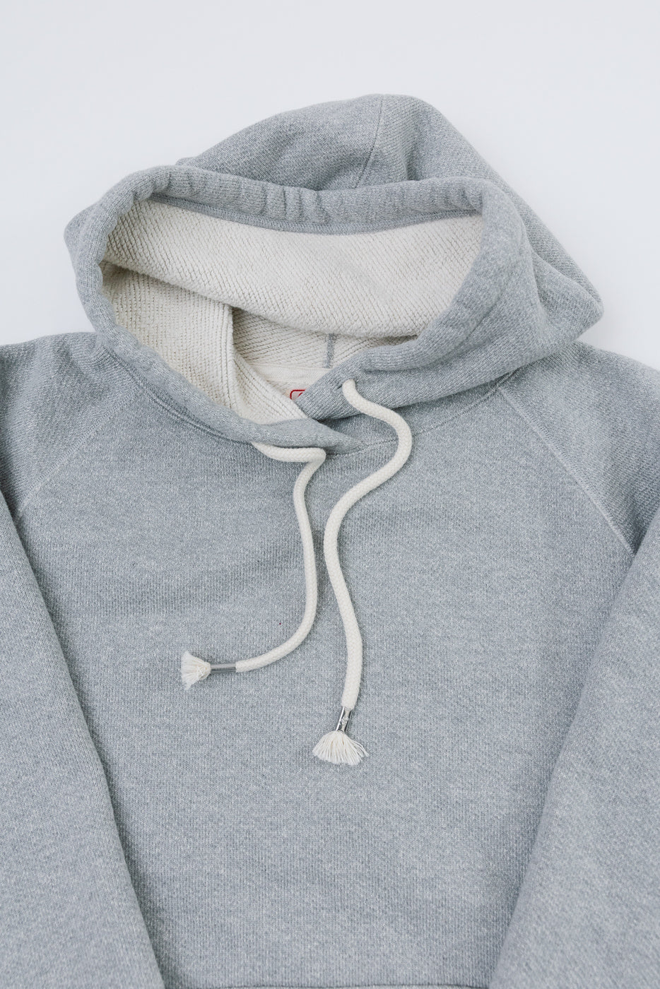 Close-up front view of a grey hoodie showing fabric texture and hood lining.