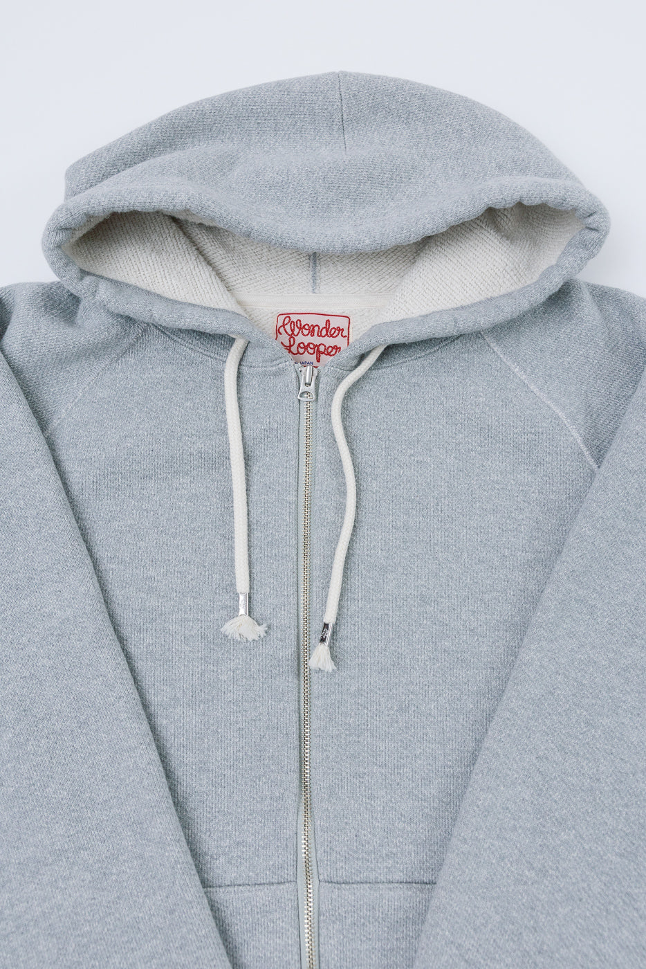 Close-up front view of a grey Wonder Loop zip-up hoodie showing the hood and tag.