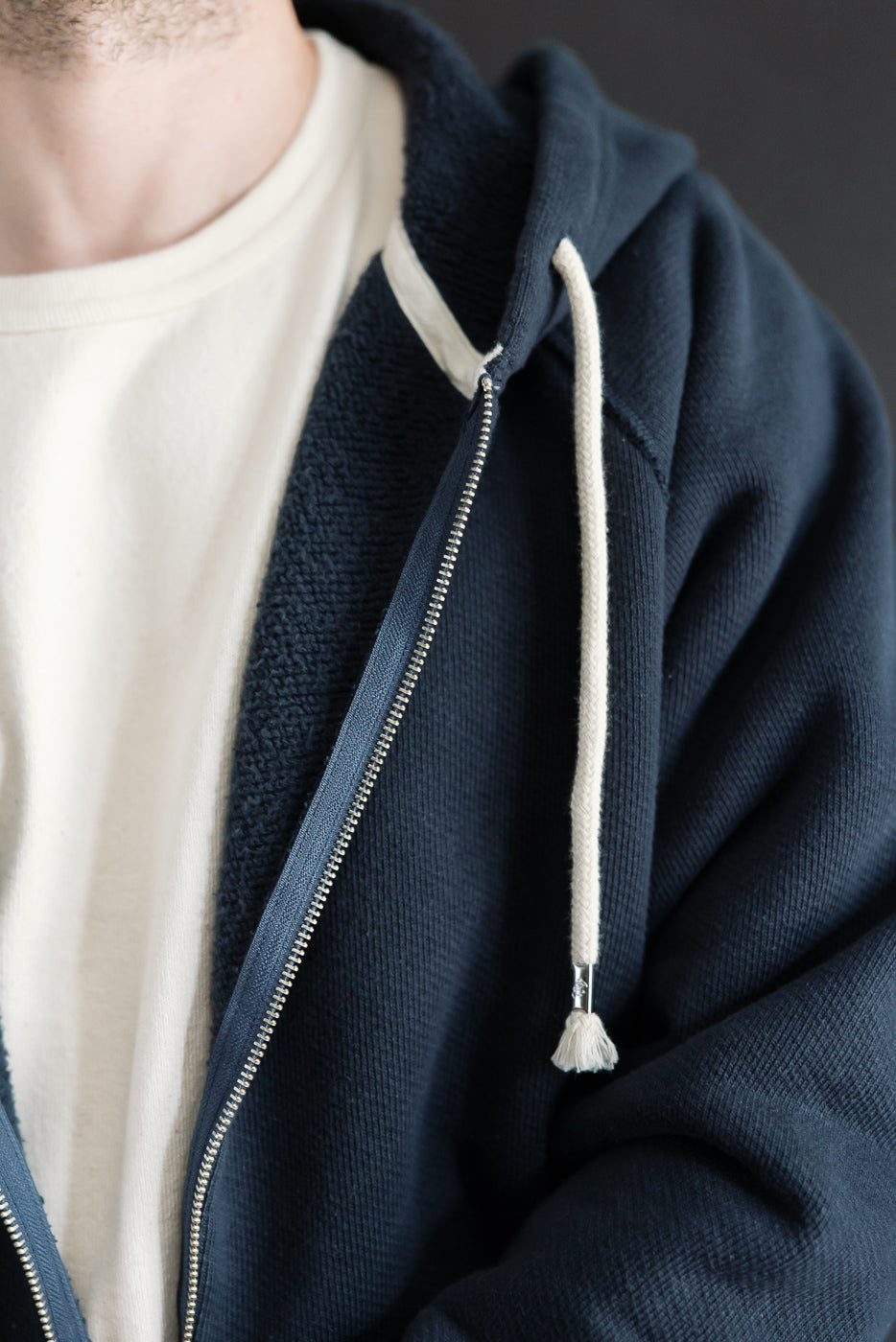 Close-up of front zipper and drawstring on a navy hoodie worn by a 5'9