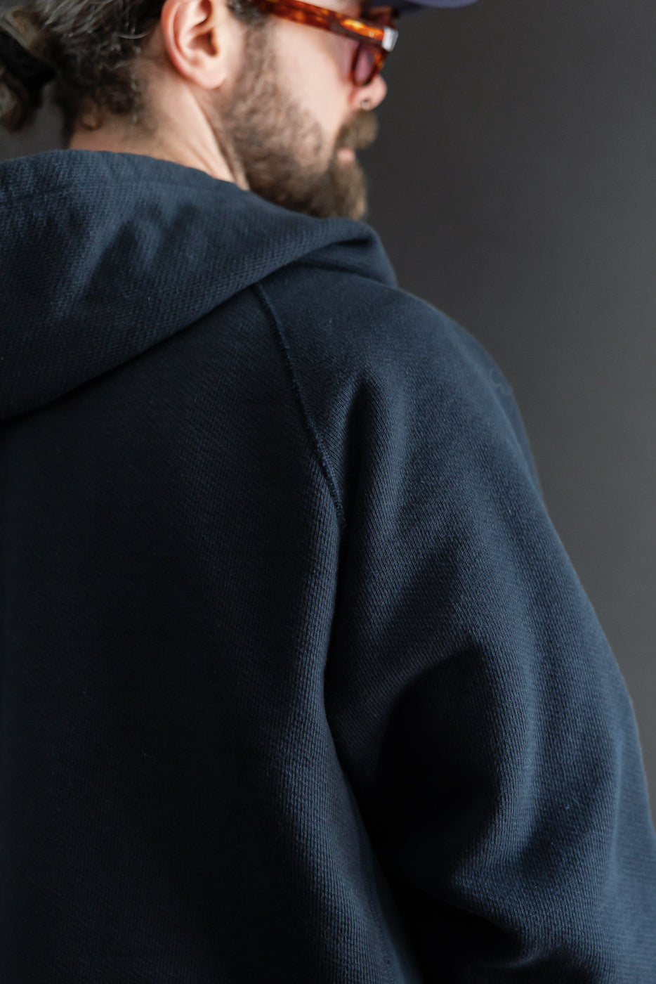 Close-up back view of a navy hoodie worn by a 5'9