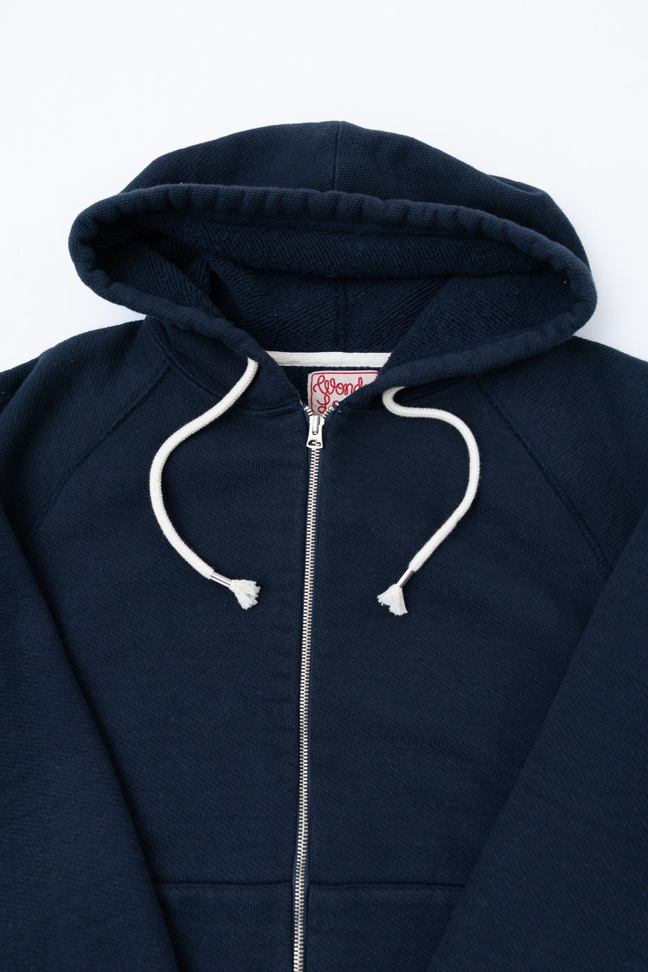 Close-up front view of a navy blue zip-up hoodie showing the hood, white drawstrings, and zipper.