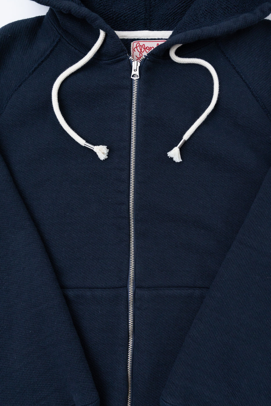 Close-up front view of a navy blue zip-up hoodie showing the silver zipper and white drawstrings.