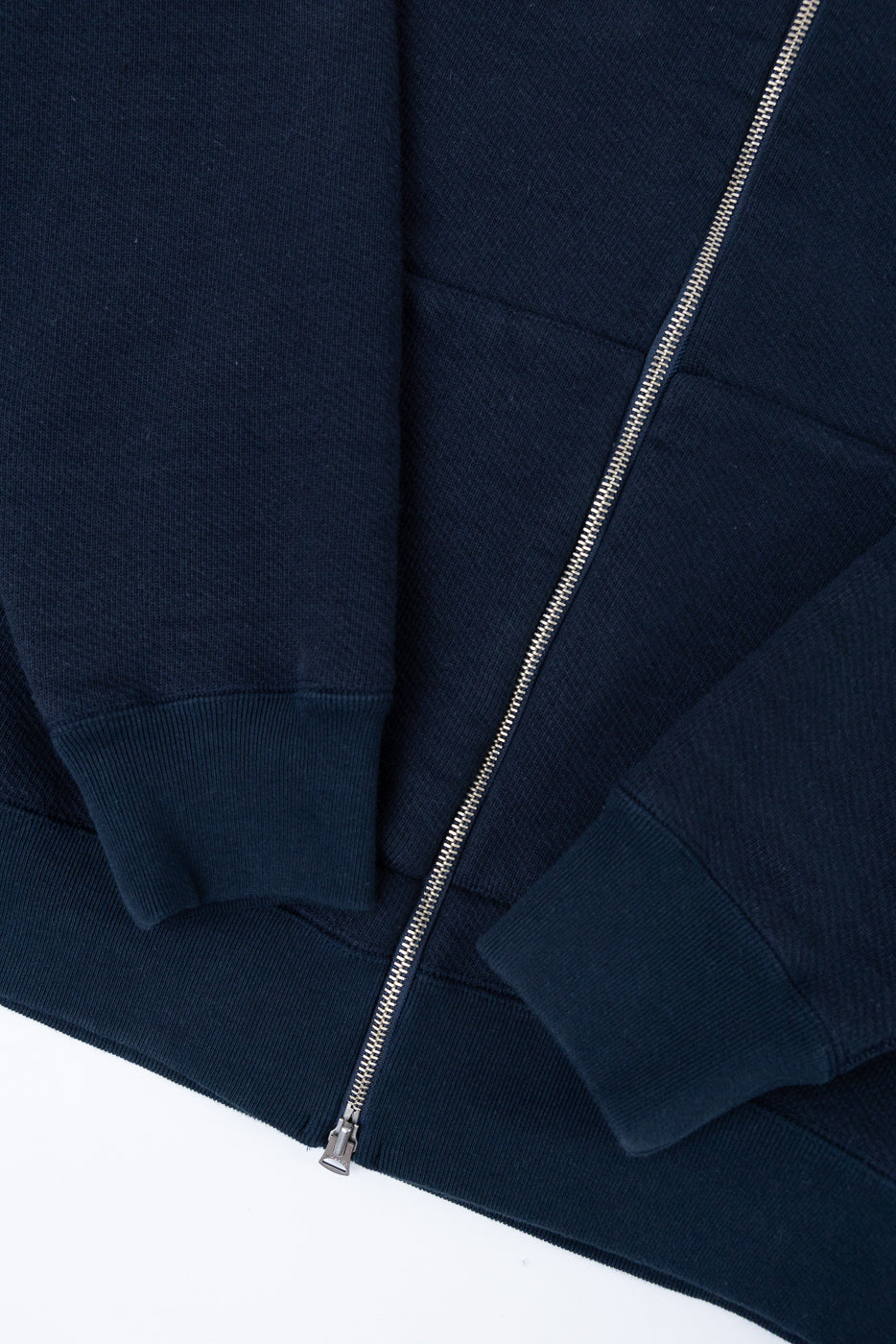 Close-up front view of a navy blue zip-up hoodie showing the silver metal zipper and fabric texture.