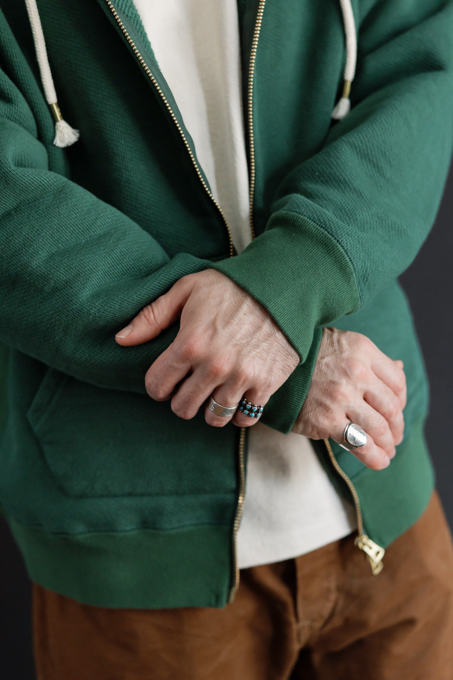 Close-up front view of a green zip-up hoodie on a male model, 5'9