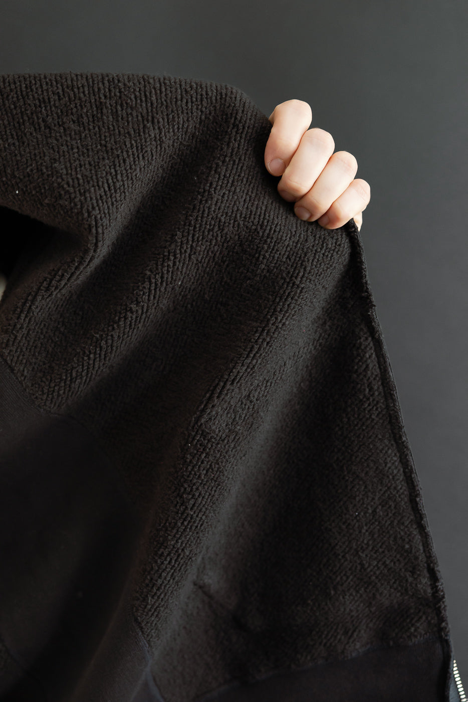 Close-up of the textured black fabric interior and hem detail of a garment.