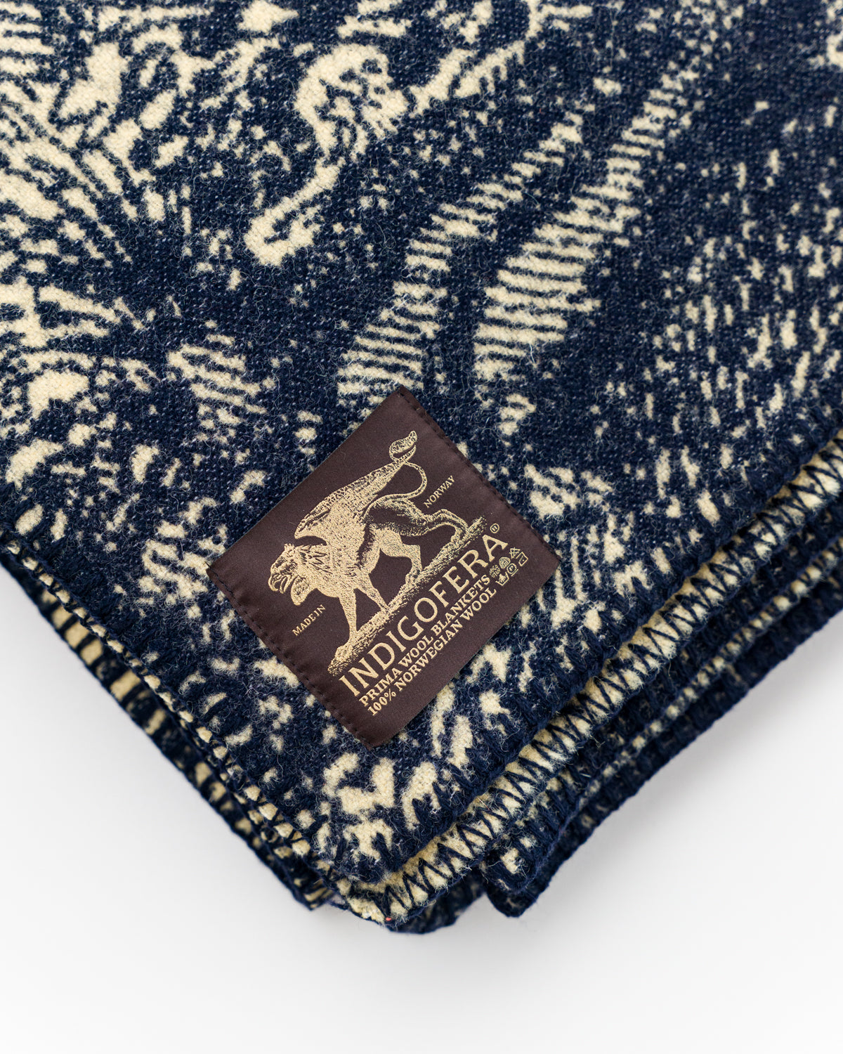 Close-up of folded blanket, beige and navy wool texture, visible woven label on front side