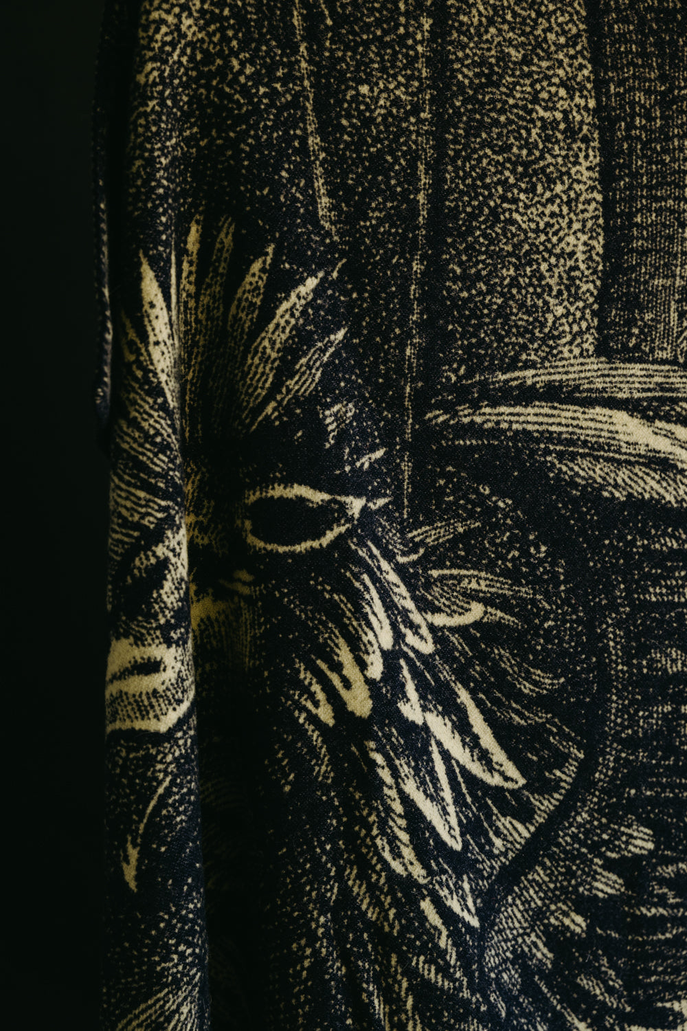 Close-up of blanket fabric texture, showing beige and navy graphic detail on side view.