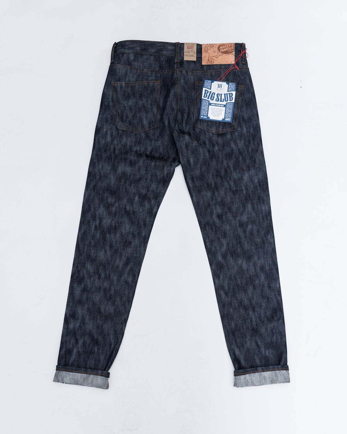 Flat lay back view of Naked & Famous Big Slub Selvedge jeans, showing rear pockets, tags, and denim texture.