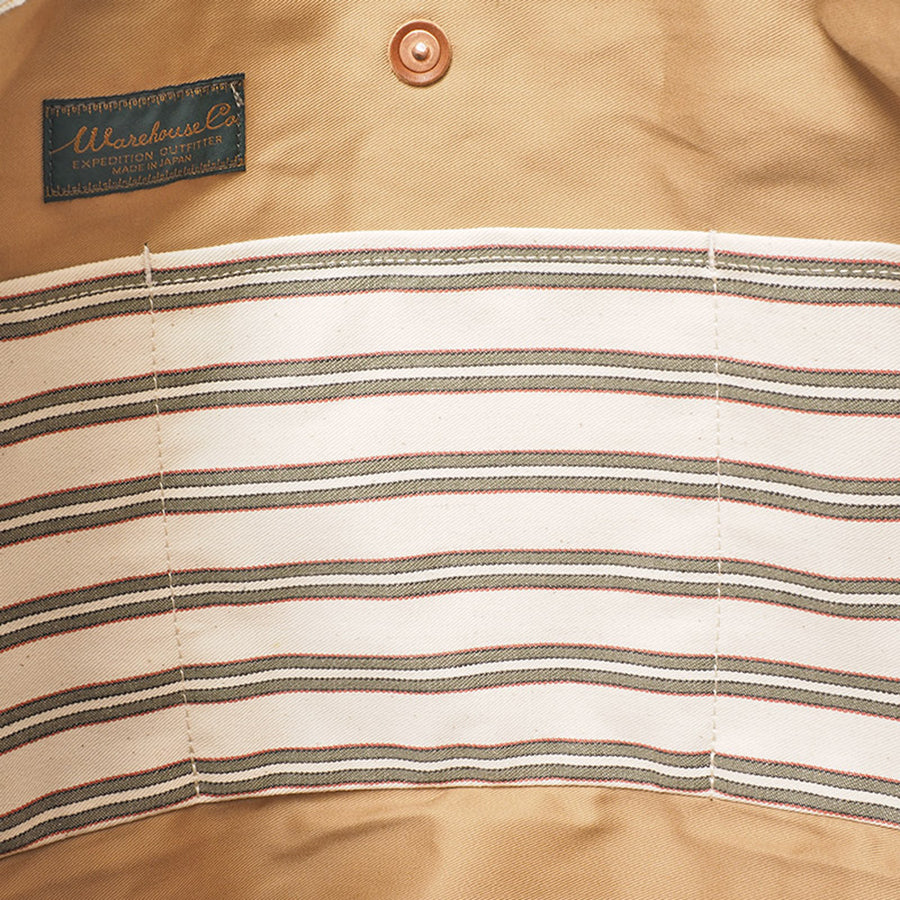 Close-up of tote bag interior showing striped fabric lining, snap closure, and inside label.